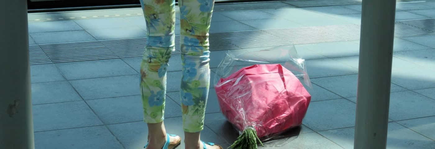 Vrouw aan tramhalte met gevallen boeket bloemen