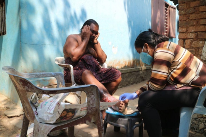 Man op straat in India wordt geholpen door een verpleegkundige.